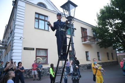 Беларусь, Брест. Фонарщик зажигает фонарь на улице города.