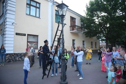Беларусь, Брест. Фонарщик зажигает фонарь на улице города.