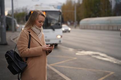 Самара. Девушка с мобильным телефоном на автобусной остановке.