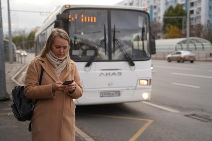 Самара. Девушка с мобильным телефоном на автобусной остановке.