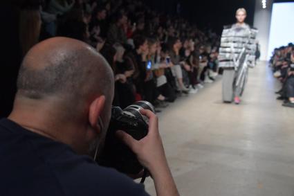 Москва. Мужчина фотографирует во время показа на неделе моды Mercedes-Benz Fashion Week Russia