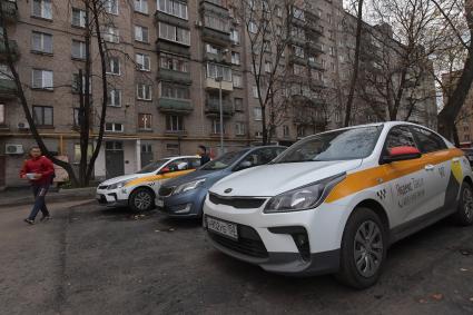 Москва.  Автомобили сервиса `Яндекс.Такси` во дворе жилого дома.