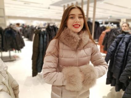 Красноярск. Девушка выбирает пуховик в магазине.