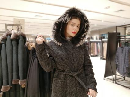 Красноярск.   Девушка выбирает пальто в магазине.