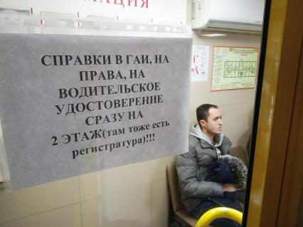 Нижний Новгород. Мужчина сидит в очереди за  медицинской справкой для водительских прав.