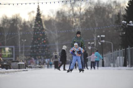 Екатеринбург. Мужчина с ребенком катаются на коньках на катке