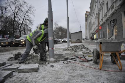 Екатеринбург. Рабочие в снег укладывают тротуарную гранитную плитку