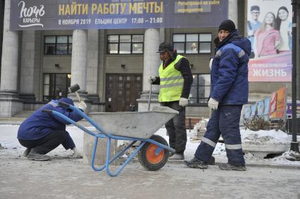 Екатеринбург. Рабочие в снег укладывают тротуарную гранитную плитку