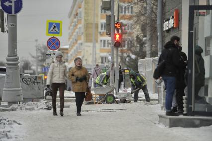 Екатеринбург. Рабочие в снег укладывают тротуарную гранитную плитку