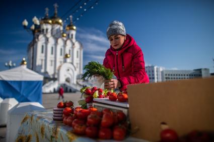 Магадан. Женщина торгует помидорами у Свято-Троицкого кафедрального собора.