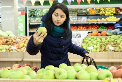 Иркутск. Девушка выбирает фрукты в продуктовом магазине.