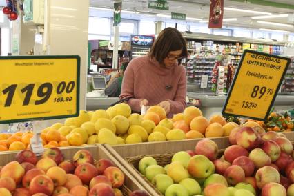 Иркутск. Женщина выбирает фрукты в продуктовом магазине.