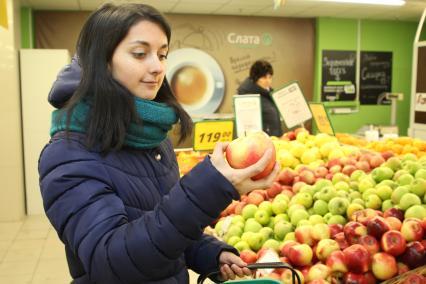 Иркутск. Девушка выбирает фрукты в продуктовом магазине.