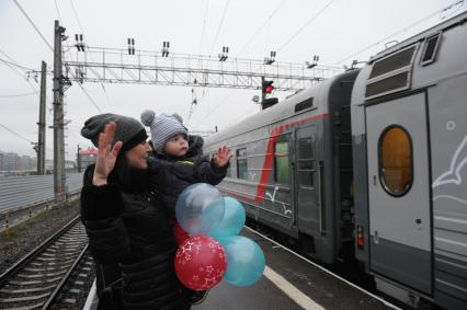 Санкт-Петербург. Женщина с ребенком проважает первый пассажирский  поезд  из Санкт-Петербурга в Севастополь через Крымский мост.