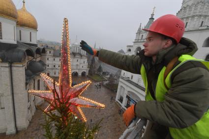 Москва.  Сотрудник коммунальных служб устанавливает  звезду на макушке новогодней елки Московского Кремля.