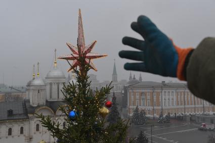 Москва.  Сотрудник коммунальных служб устанавливает  звезду на макушке новогодней елки Московского Кремля.