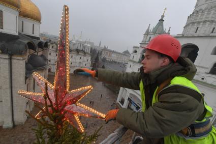 Москва.  Сотрудник коммунальных служб устанавливает  звезду на макушке новогодней елки Московского Кремля.