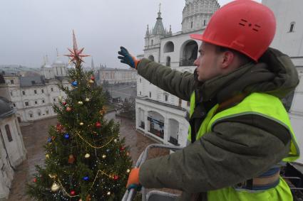 Москва.  Сотрудник коммунальных служб устанавливает  звезду на макушке новогодней елки Московского Кремля.