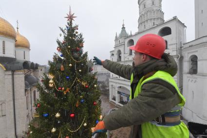 Москва.  Сотрудник коммунальных служб устанавливает  звезду на макушке новогодней елки Московского Кремля.