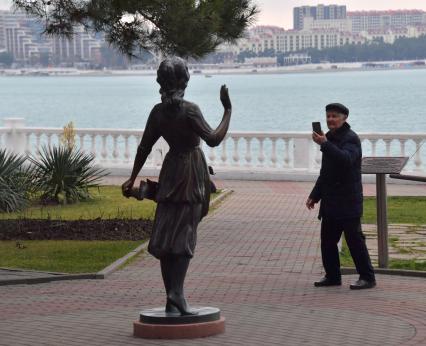 Геленджик. Мужчина фотографирует скульптуру на набережной.