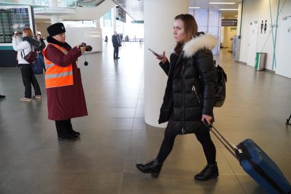 Самара. Сотрудник Роспотребнадзора проверяет тепловизором пассажиров прибывшего самолета.