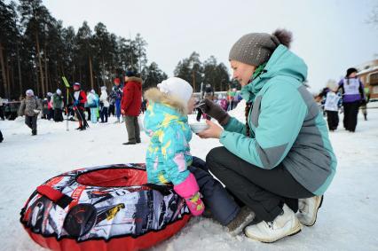 Екатеринбург. Женщина кормит ребенка солдатской кашей во время массового забега на лыжах \'Лыжня России 2020\'.
