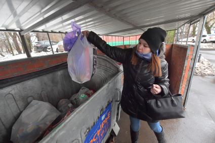 Москва. Девушка выбрасывает мусор в уличный контейнер.