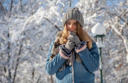 Пермь.  Девушка пьет кофе на улице зимой.