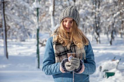 Пермь.  Девушка пьет кофе на улице зимой.