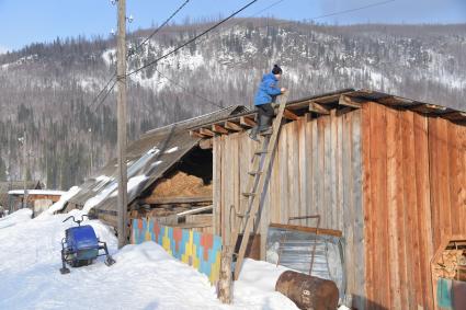 Красноярский край, пос. Бурный.  Мальчик залезает на крышу сарая.