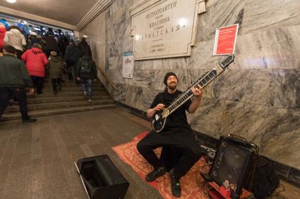 Москва.  Мужчина  играет на ситаре на станции метро `Арбатская`.