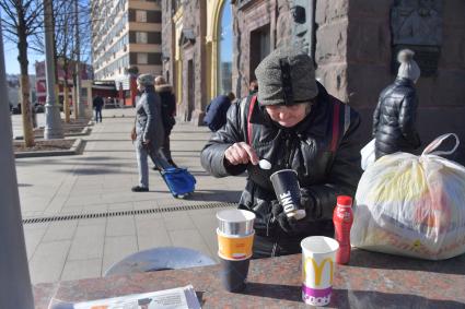 Москва. Пожилая женщина ест  на Тверской улице.