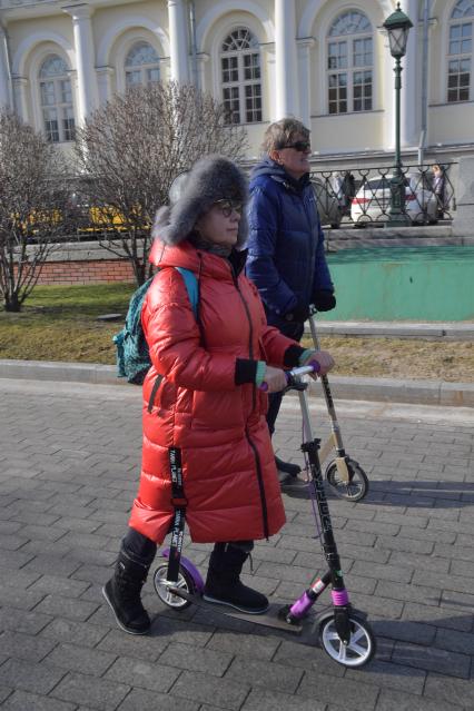 Москва. Туристы на самокатах на Манежной улице.