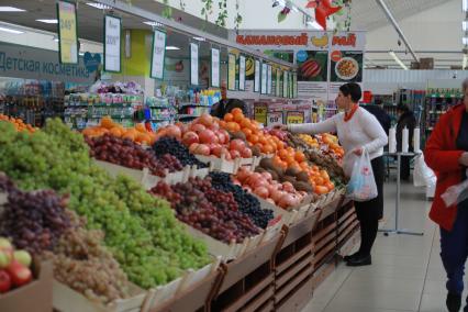 Красноярск.  Женщина выбирает фрукты в магазине.
