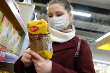 Санкт-Петербург. Покупательница в медицинской маске  в магазине  у полок с товаром.