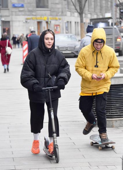 Москва. Девушка на самокате и юноша на скейтборде.