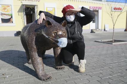 Барнаул. Девушка в медицинской маске рядом со скульптурой медведя.