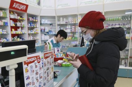 Барнаул. Девушка в медицинской маске в аптеке.