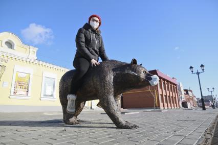 Барнаул. Девушка в медицинской маске рядом со скульптурой медведя.