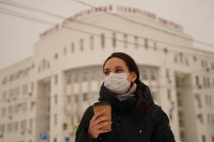 Самара. Девушка в медицинской маске  с пластиковым одноразовым стаканчиком на улице.