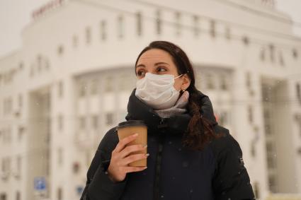 Самара. Девушка в медицинской маске  с пластиковым одноразовым стаканчиком на улице.