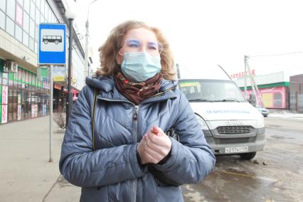Иркутск. Девушка в медицинской маске на остановке общественного транспорта.