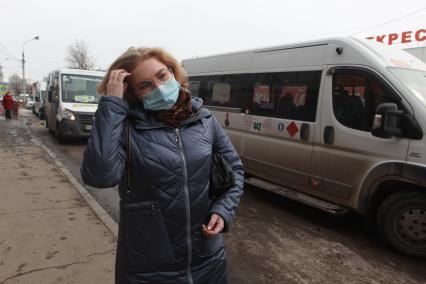 Иркутск. Девушка в медицинской маске на остановке общественного транспорта.