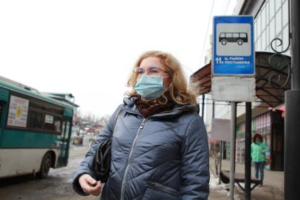 Иркутск. Девушка в медицинской маске  на остановке  общественного транспорта.