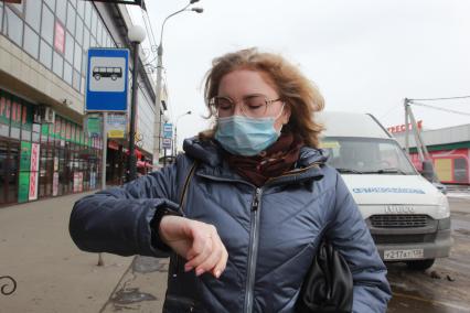 Иркутск. Девушка в медицинской маске на остановке общественного транспорта.