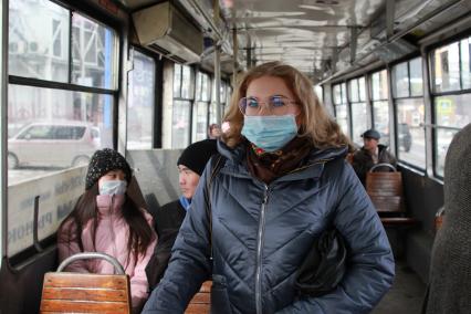 Иркутск. Девушка в медицинской маске едет в общественном транспорте.