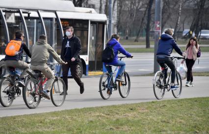 Москва.   Велосипедисты и мужчина в медицинской маске на улице города.