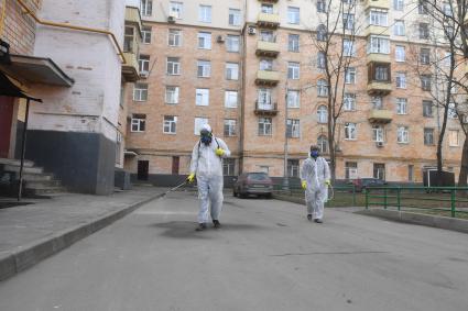 Москва. Сотрудники коммунальной службы в защитных костюмах во время дезинфекции двора жилого дома.