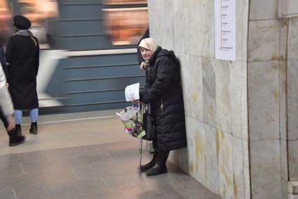 Москва. Пожилая женщина просит милостыню в метро.