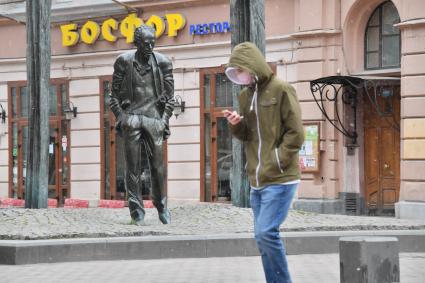 Москва.  Молодой человек в медицинской маске  у памятника Булату Окуджаве на Старом Арбате.